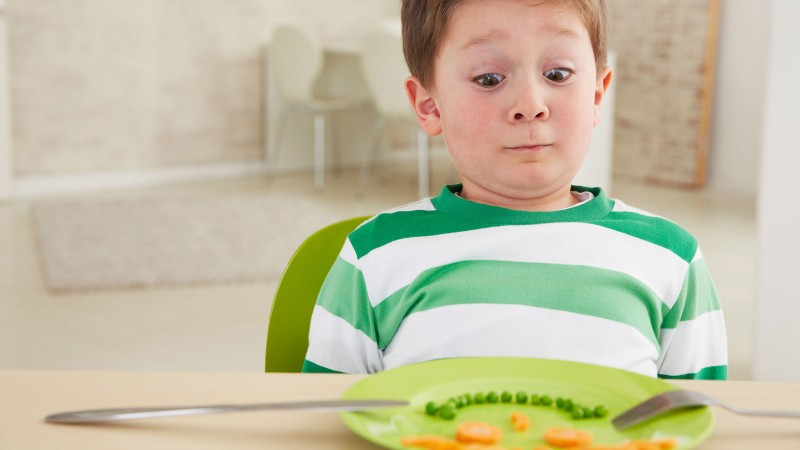 Junge schaut unsicher auf Teller