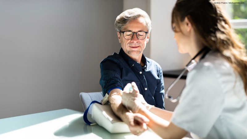 Mann bekommt von Ärztin Blutdruck gemessen