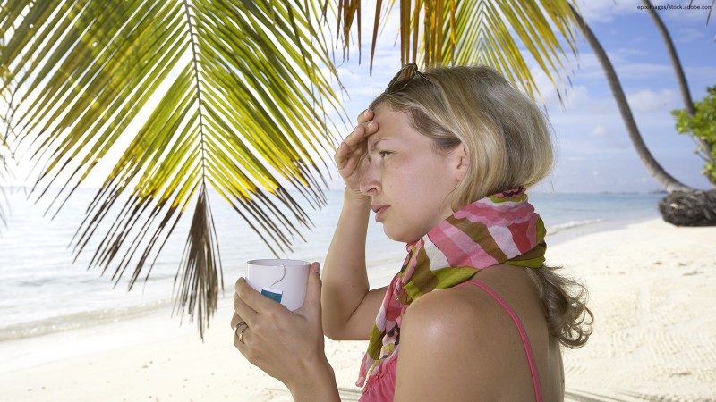 Frau am Strand mit Kopfschmerzen