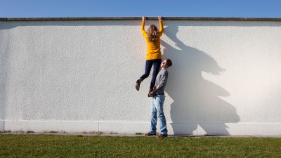 Mann hilft Frau über Mauer