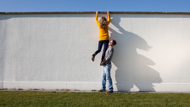 Mann hilft jemand über Mauer