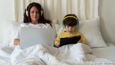Mutter und Sohn im Bett. Beide schauen sich etwas an.