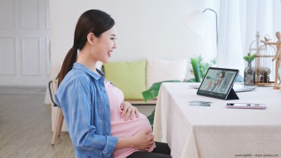 A pregnant woman sitting in front of a laptop. 