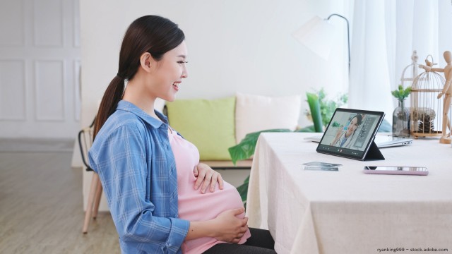 A pregnant woman sitting in front of a laptop. 