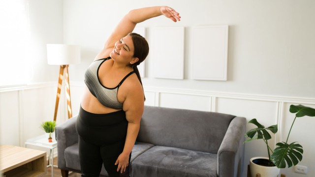 Frau macht Dehnübungen zuhause