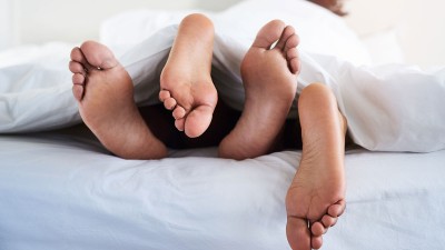 Füße schauen unter der Bettdecke hervor.