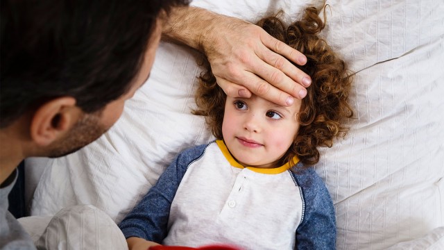 Vater hält Hand auf die Stirn vom Kind.