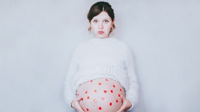 Frau mit Herzen auf Babybauch