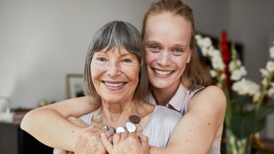 Frau umarmt Mutter von hinten