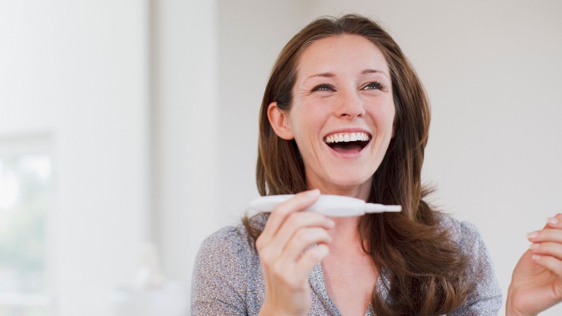 glückliche Frau mit Schwangerschaftstest