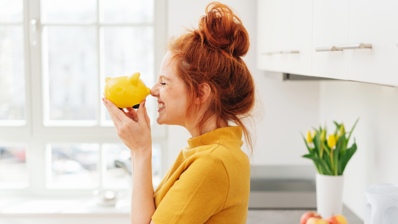 Frau grinst Sparschwein an