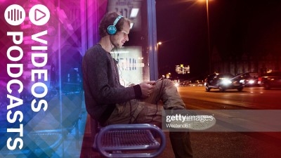 Mann mit Kopfhörern an Bushaltestelle