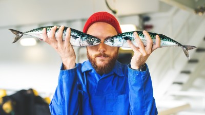 Mann hält zwei Fische vor dem Gesicht
