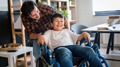 Vater spielt mit seinem Kind im Rollstuhl