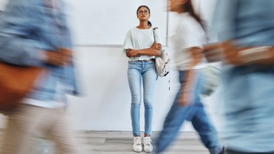 Eine junge Frau steht in einer Menge von Menschen, die in Bewegung sind.