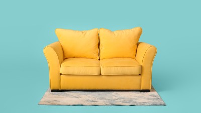 Ein gelbes Sofa steht auf einem Teppich vor hellblauem Hintergrund