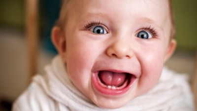 Ein Baby schaut lustig in die Kamera, mit aufgerissenen Augen und aufgerissenem Mund.