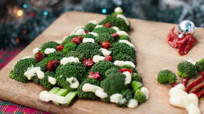 Ein Weihnachtsbaum aus Brokkoli und rotem Gemüse ist auf einem Schneidebrett aus Holz angerichtet