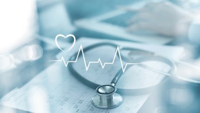 Stethoskop auf einem EKG-Diagramm mit digital eingeblendetem Herzsymbol und Herzlinie.