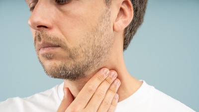 Mann tastet mit der Hand seine geschwollenen Lymphknoten am Hals ab.