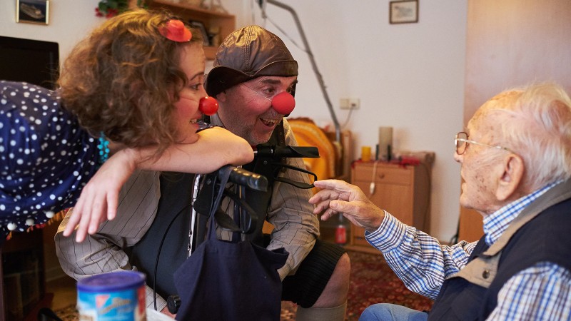 Personen mit roter Clownsnase bei einem älteren Mann