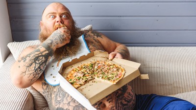 Mann auf Couch isst Pizza