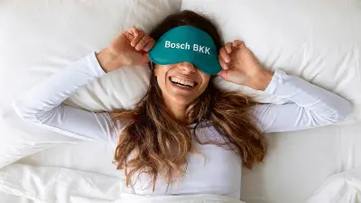 Frau mit Schlafmaske liegt im Bett