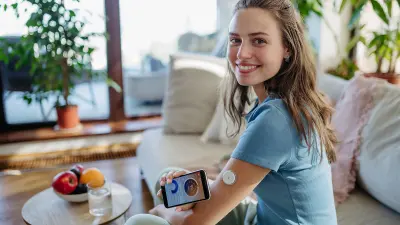 Eine junge Frau misst ihren Zuckerwert über einen Sensor am Arm.
