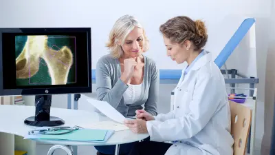 Eine Patientin und eine Ärztin sitzen gemeinsam vor einem Bildschirm im Behandlungszimmer.