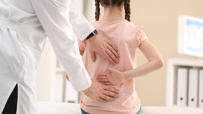 Ein Arzt untersucht den Rücken eines jungen Mädchen.