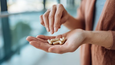Eine Frau hält mehrere beige Kapseln in ihrer Hand.