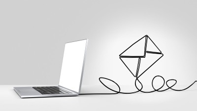 Laptop mit Ladekabel in Form eines Briefes