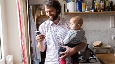 Mann mit Handy und Kind auf dem Arm