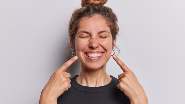 Frau zeigt auf ihr Lächeln