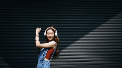 Junge Asiatin mit Kopfhörern, tanzend vor einem Garagentor