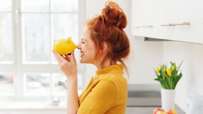 Frau grinst Sparschwein an